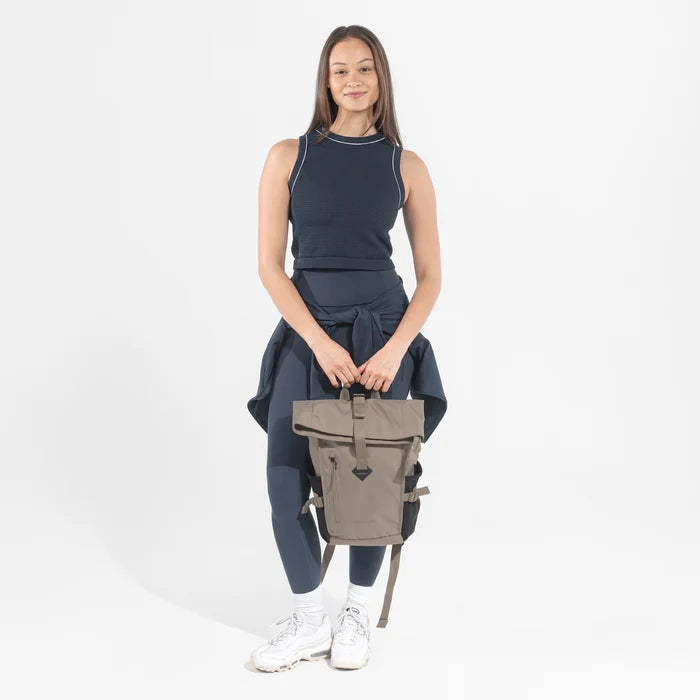 Woman wearing a Sherpani Sedona Dune Backpack on her back against white background. #color_dune-tan