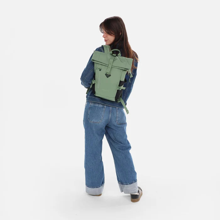 Woman wearing a Sherpani Sedona Olivine Backpack on her back against white background.  #color_olivine-green