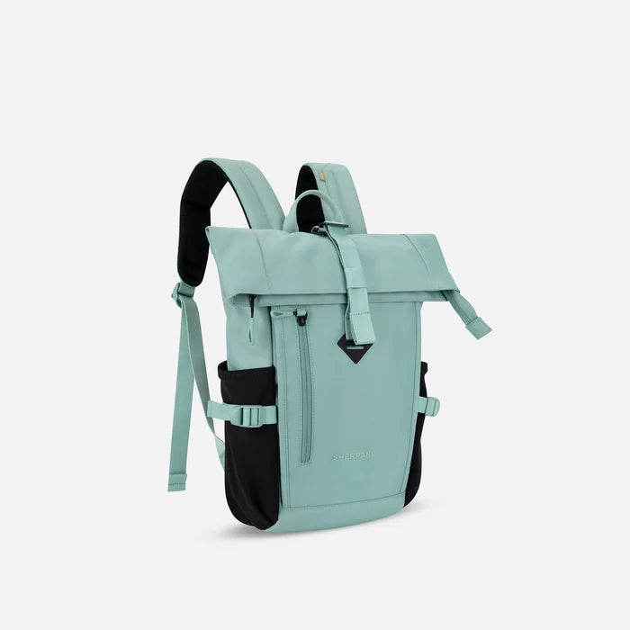 A Sherpani Sedona Surf Blue Backpack, 3/4 view showing buckled pockets and straps on white background.   #color_surf-blue