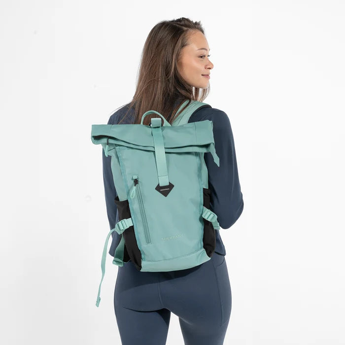 Woman wearing a Sherpani Sedona Surf Blue Backpack on her back against white background. #color_surf-blue