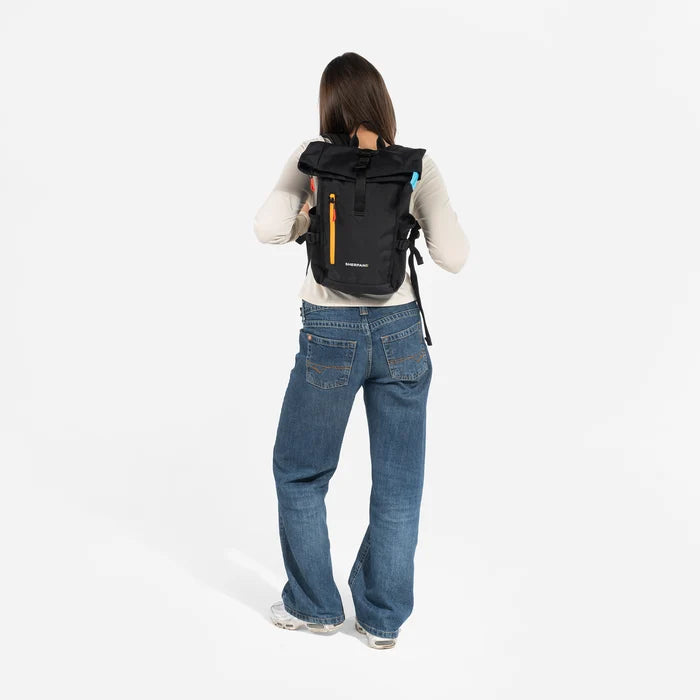 Woman wearing a Sherpani Sedona Chromatic Black Backpack on her back against white background. #color_chromatic-black