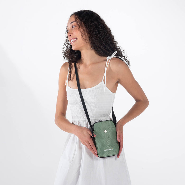 Woman wearing a Sherpani Simplicity Aloe Mist Green Crossbody Wallet against white backdrop. #color_aloe-mist-green