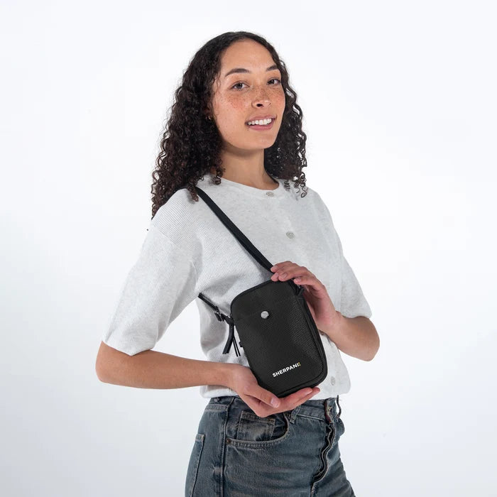 Woman wearing a Sherpani Simplicity Carbon Black Anti-Theft Crossbody Wallet on her shoulder against white backdrop.  #color_carbon-black