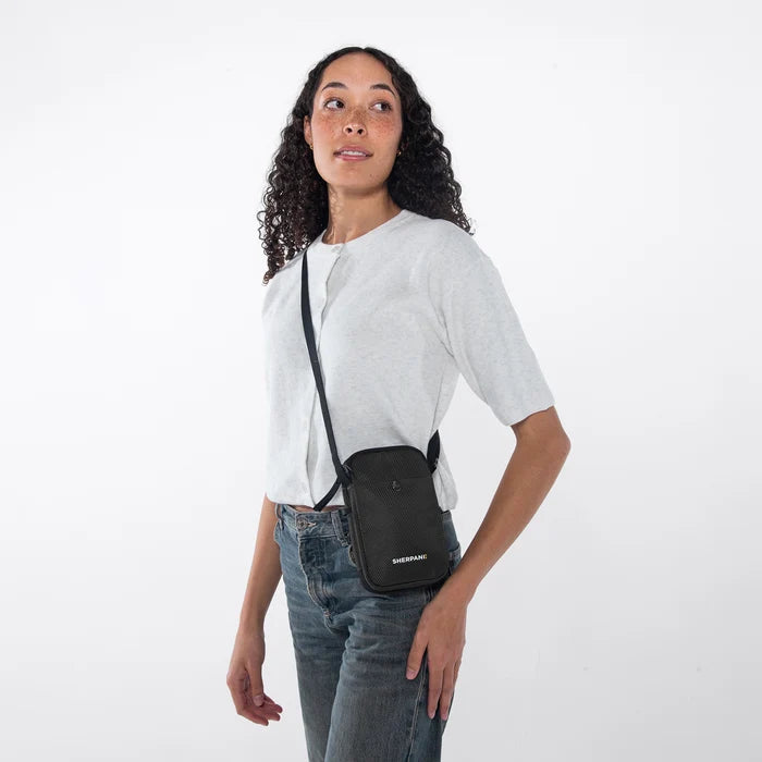 Woman wearing a Sherpani Simplicity Carbon Black Anti-Theft Crossbody Wallet on her shoulder against white backdrop.  #color_carbon-black