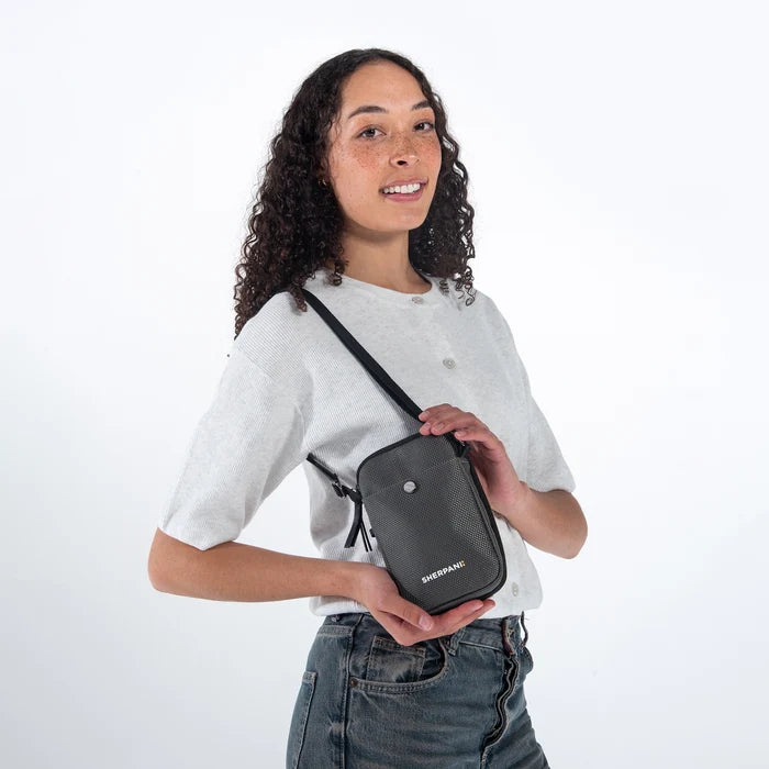 Woman wearing a Sherpani Simplicity Granite Anti-Theft Crossbody Wallet on her shoulder against white backdrop.  #color_granite-grey