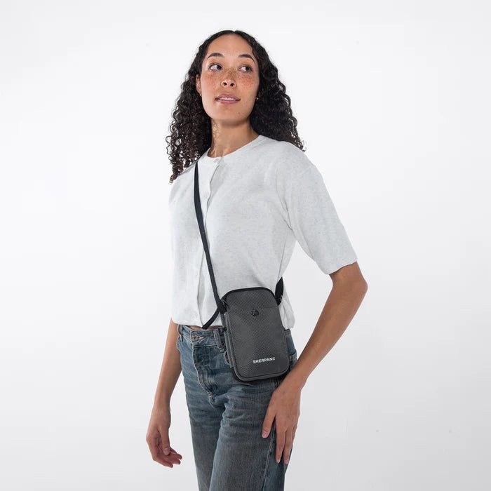 Woman wearing a Sherpani Simplicity Granite Anti-Theft Crossbody Wallet on her shoulder against white backdrop.  #color_granite-grey