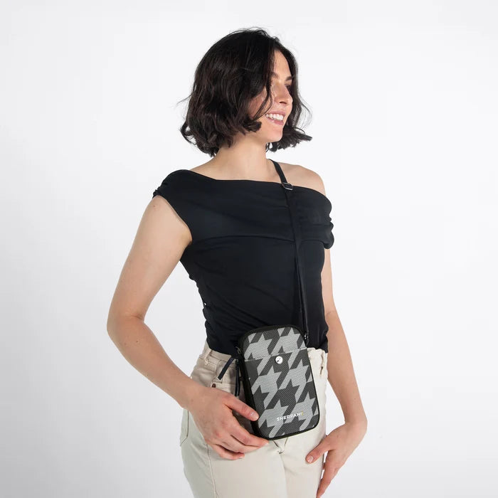 Woman wearing a Sherpani Simplicity  Houndstooth Anti-Theft Crossbody Wallet on her shoulder against white backdrop.  #color_houndstooth-print