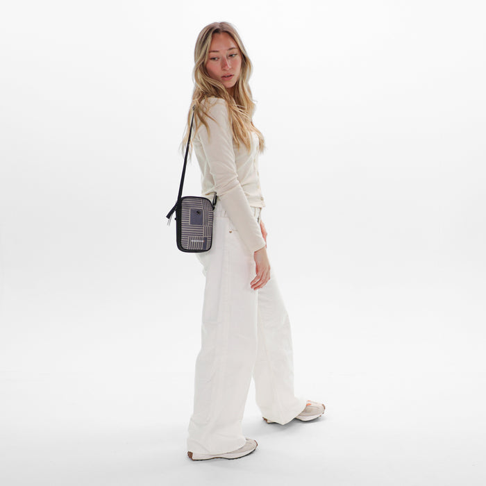 Woman wearing a Sherpani Simplicity Passport Anti-Theft Crossbody Wallet on her shoulder against white backdrop.  #color_passport-print