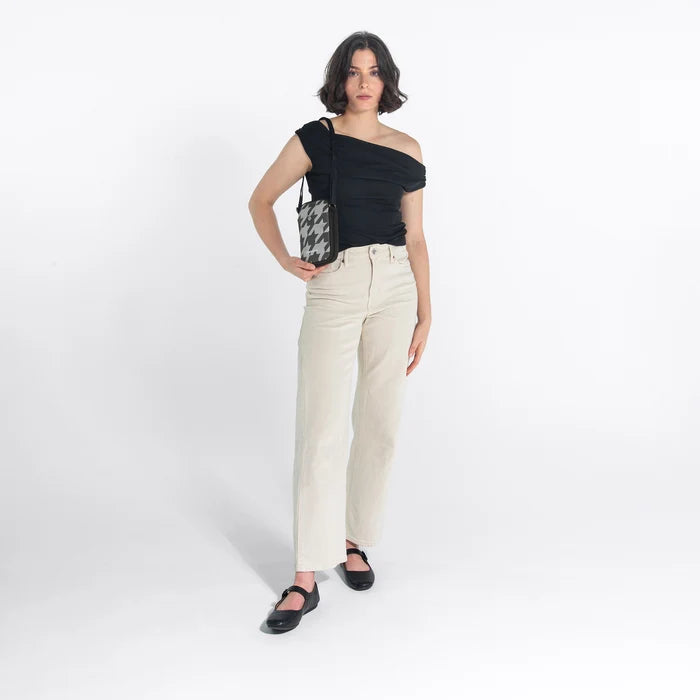 Woman wearing a Sherpani Simplicity  Houndstooth Anti-Theft Crossbody Wallet on her shoulder against white backdrop. #color_houndstooth-print