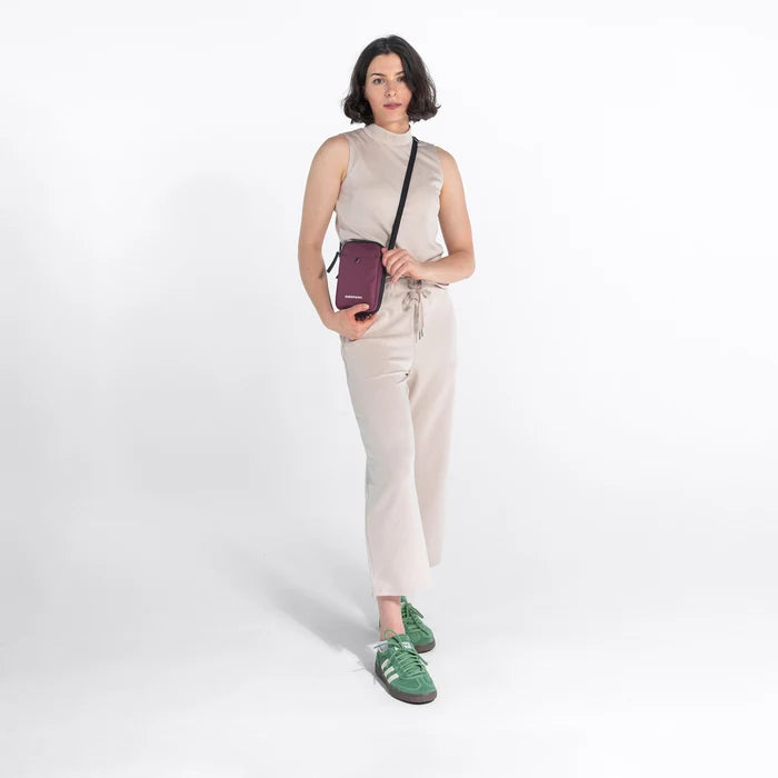 Woman wearing a Sherpani Simplicity  Smoky Orchid Anti-Theft Crossbody Wallet on her shoulder against white backdrop.  #color_smoky-orchid-pink