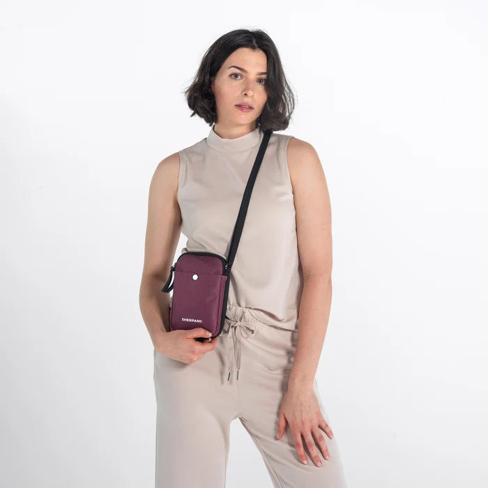 Woman wearing a Sherpani Simplicity Smoky Orchid Anti-Theft Crossbody Wallet on her shoulder against white backdrop.  #color_smoky-orchid-pink
