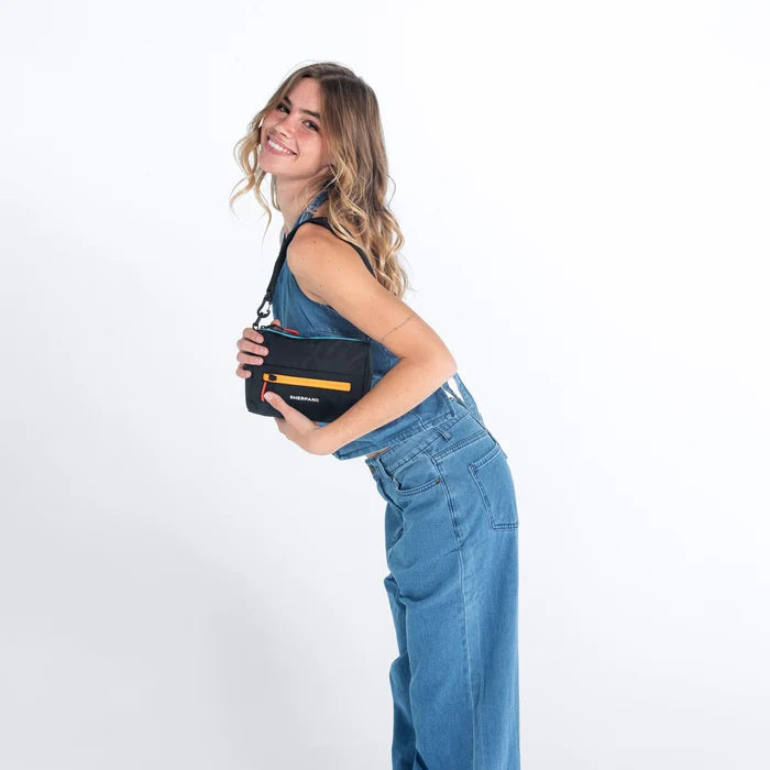 Woman wearing a Sherpani Skye Chromatic Black Shoulder Bag by short strap against white backdrop. #color_chromatic-black