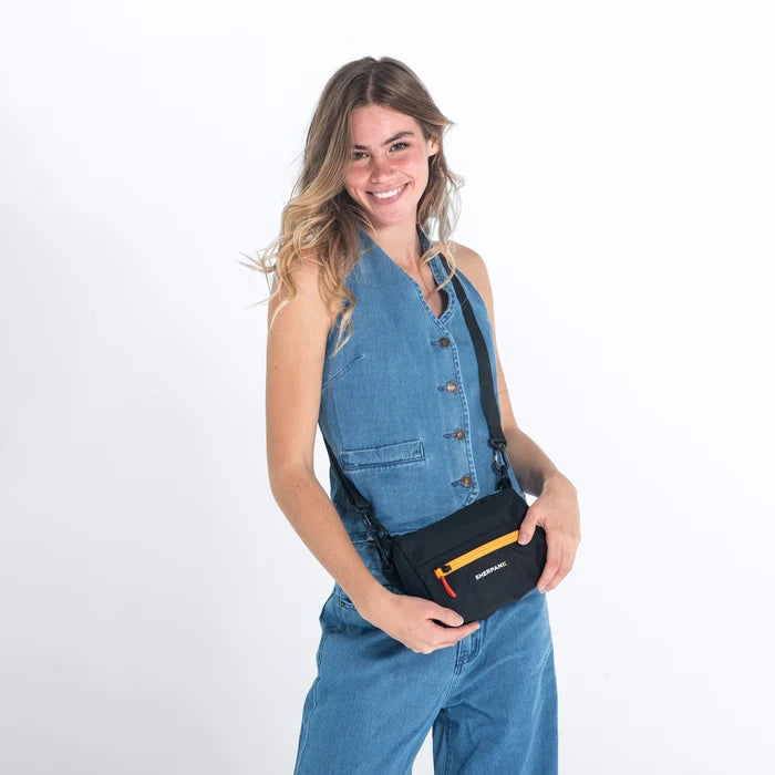 Woman wearing a Sherpani Skye Chromatic Black Shoulder Bag by short strap against white backdrop. #color_chromatic-black