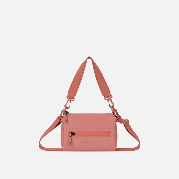 A Sherpani Desert Pink Shoulder Bag, front view showing lockable pocket and strap options on white backdrop.  #color_desert-pink