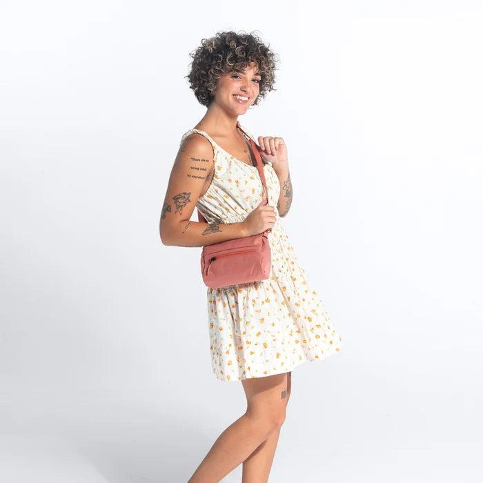 Woman wearing a Sherpani Skye Desert Shoulder Bag against white backdrop. #color_desert-pink