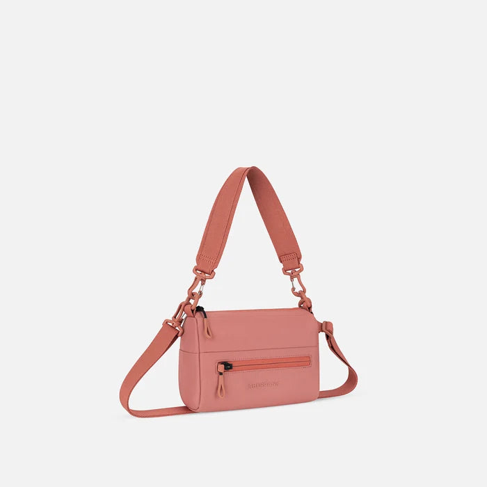 A Sherpani Skye Desert Pink Shoulder Bag, 3/4 view showing lockable pocket and strap options on white backdrop.  #color_desert-pink