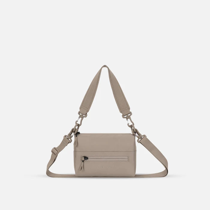 A Sherpani Dune Shoulder Bag, front view showing lockable pocket and strap options on white backdrop.  #color_dune-tan
