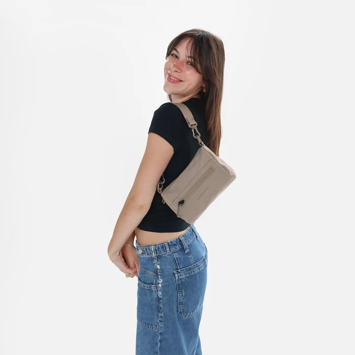 Woman wearing a Sherpani Skye Dune Shoulder Bag by short strap against white backdrop.  #color_dune-tan