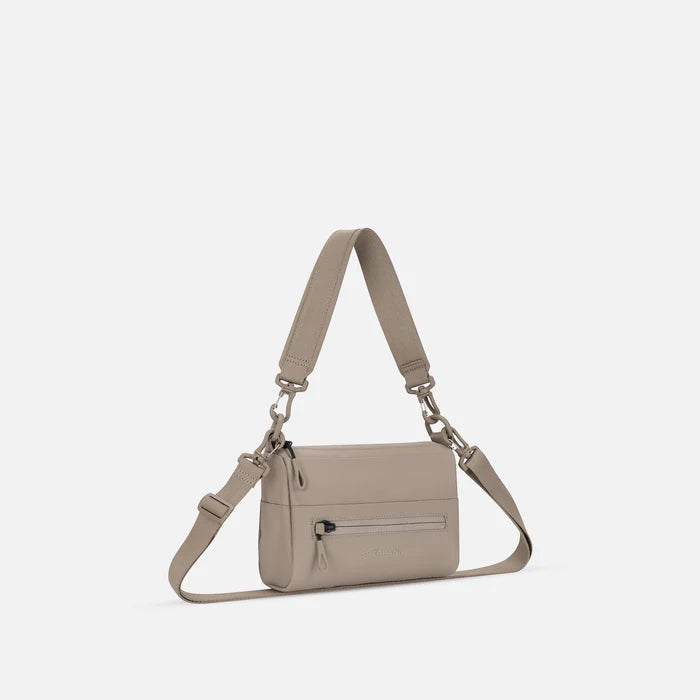 A Sherpani Skye Dune Shoulder Bag, 3/4 view showing lockable pocket and strap options on white backdrop.  #color_dune-tan