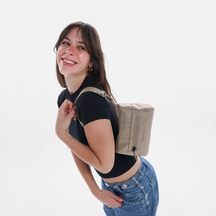 Woman wearing a Sherpani Skye Dune Shoulder Bag by short strap against white backdrop. #color_dune-tan