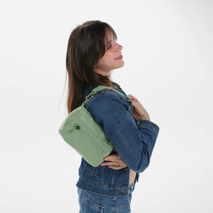 Woman wearing a Sherpani Skye Olivine Shoulder Bag by short strap against white backdrop. #color_olivine-green