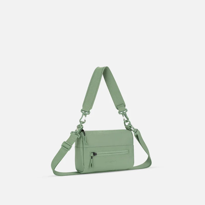A Sherpani Skye Olivine Shoulder Bag, 3/4 view showing lockable pocket and strap options on white backdrop.  #color_olivine-green