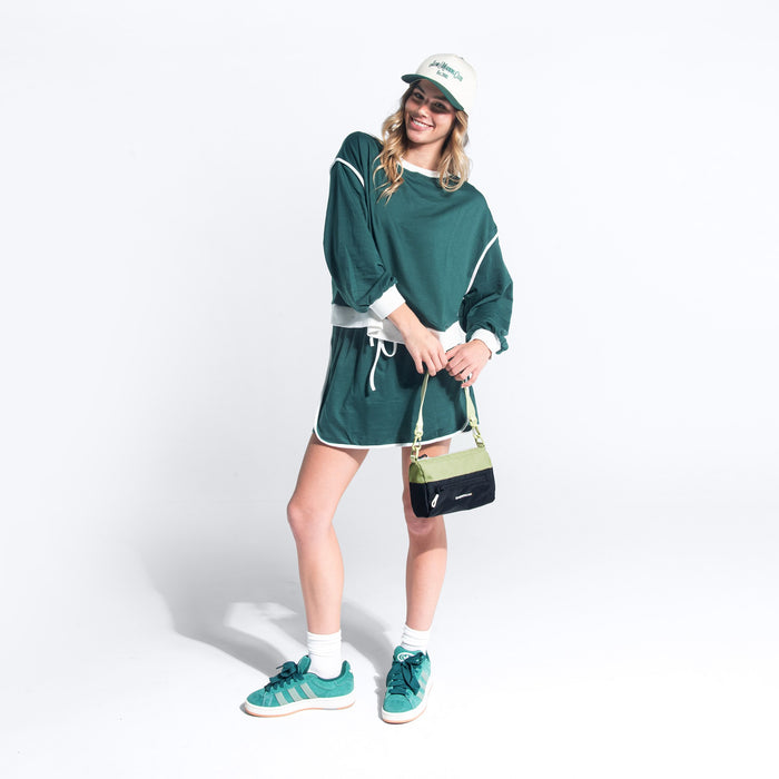 Woman wearing a Sherpani Skye Palm Green Shoulder Bag by short strap against white backdrop. #color_palm-green