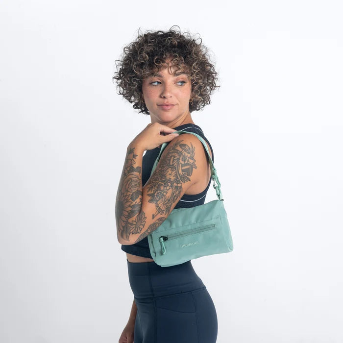Woman wearing a Sherpani Skye Surf Blue Shoulder Bag by short strap against white backdrop. #color_surf-blue