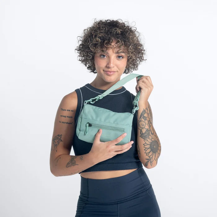 Woman wearing a Sherpani Skye Surf Blue Shoulder Bag by short strap against white backdrop. #color_surf-blue