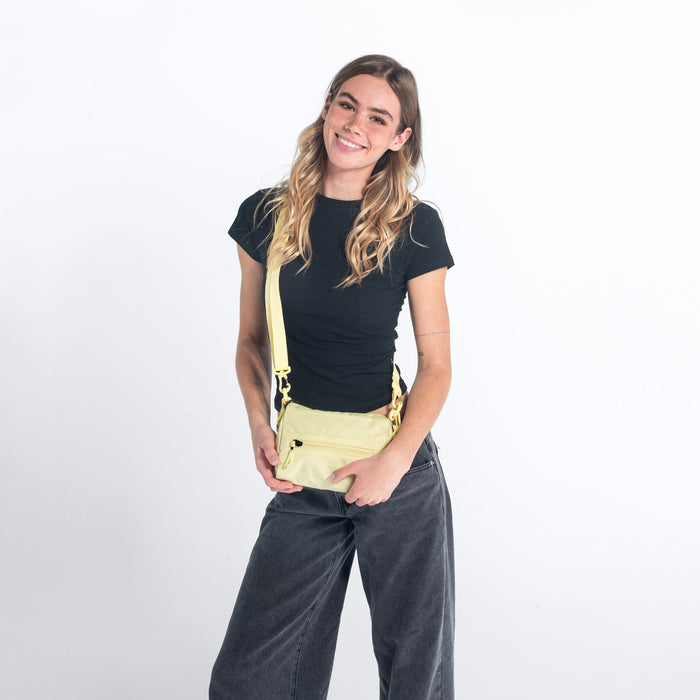 Woman wearing a Sherpani Skye Sol Yellow Shoulder Bag against white backdrop. #color_sol-yellow