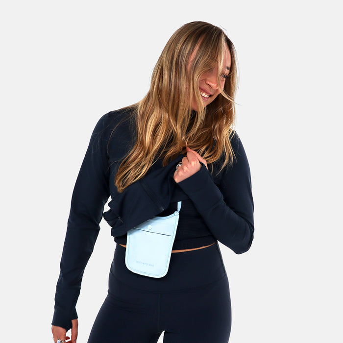 Woman wearing a Sherpani Soft Touch Concealed Neck Wallet Cool Blue around her neck on white background.