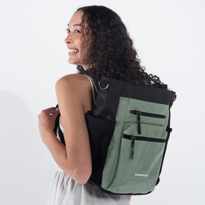 Woman wearing Sherpani Soleil Aloe Mist Green Anti-theft Multi-Wear Travel Bag on her back against white backdrop.  #color_aloe-mist-green