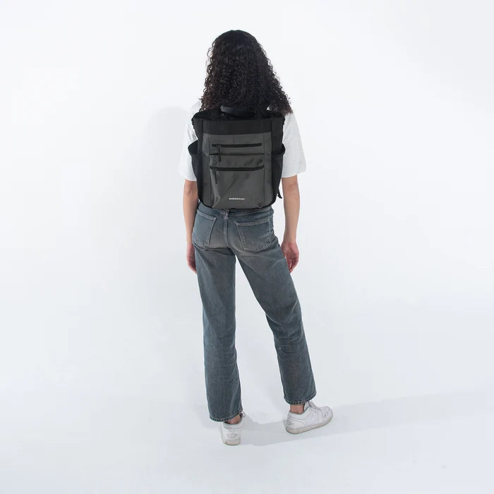Woman holding Sherpani Soleil Granite Anti-theft Multi-Wear Travel Bag by backpack straps on white backdrop. #color_granite-grey