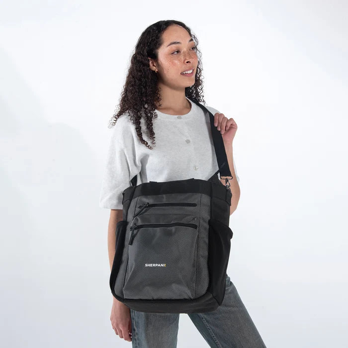 Woman holding Sherpani Soleil Granite Anti-theft Multi-Wear Travel Bag by Crossbody straps on white backdrop. #color_granite-grey