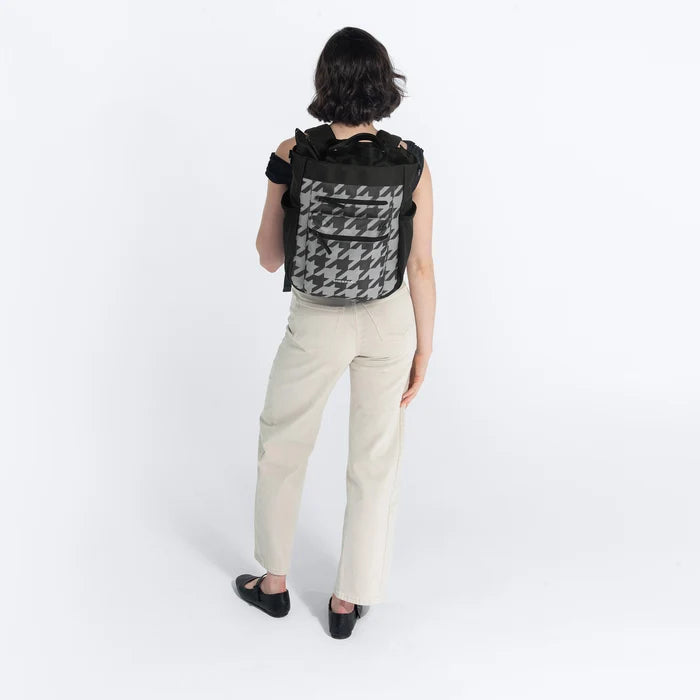 Woman holding Sherpani Soleil Houndstooth Anti-theft Multi-Wear Travel Bag by backpack straps on white backdrop. #color_houndstooth-print