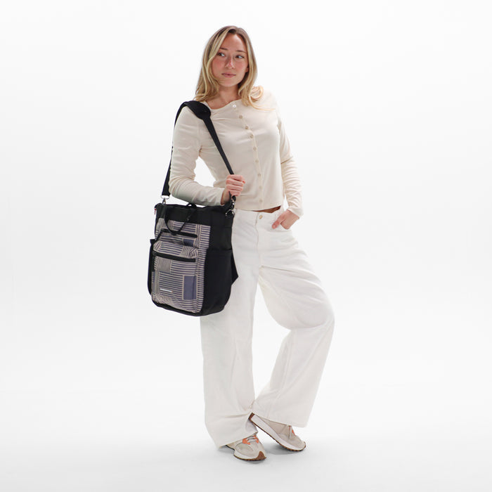 Woman holding Sherpani Soleil Passport Anti-theft Multi-Wear Travel Bag by crossbody straps on white backdrop. #color_passport-print