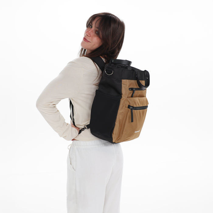 Woman holding Sherpani Soleil Sand Anti-theft Multi-Wear Travel Bag by backpack straps on white backdrop. #color_sand-tan