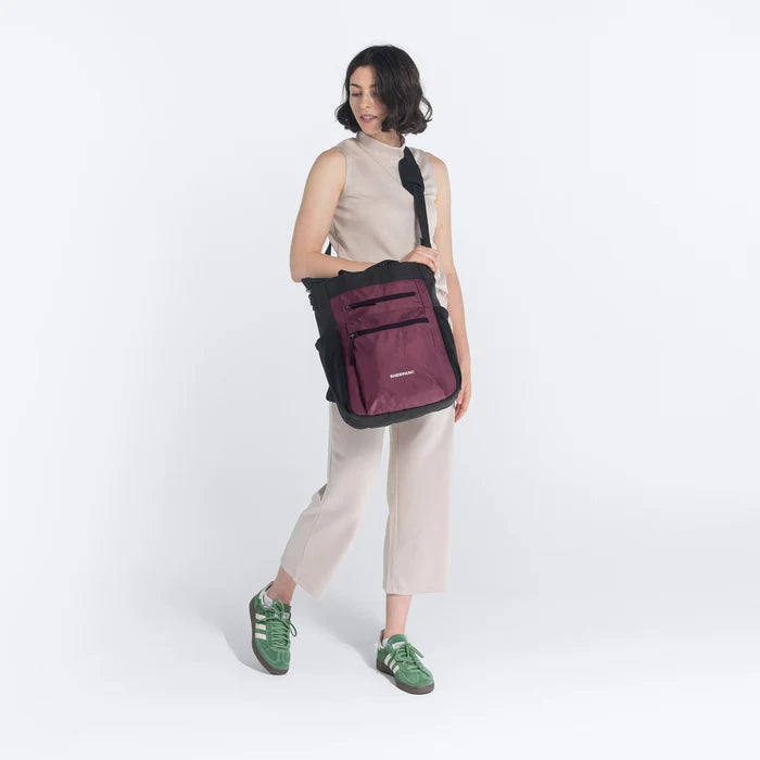 Woman holding Sherpani Soleil Smoky Orchid Anti-theft Multi-Wear Travel Bag by crossbody straps on white backdrop. #color_smoky-orchid-pink