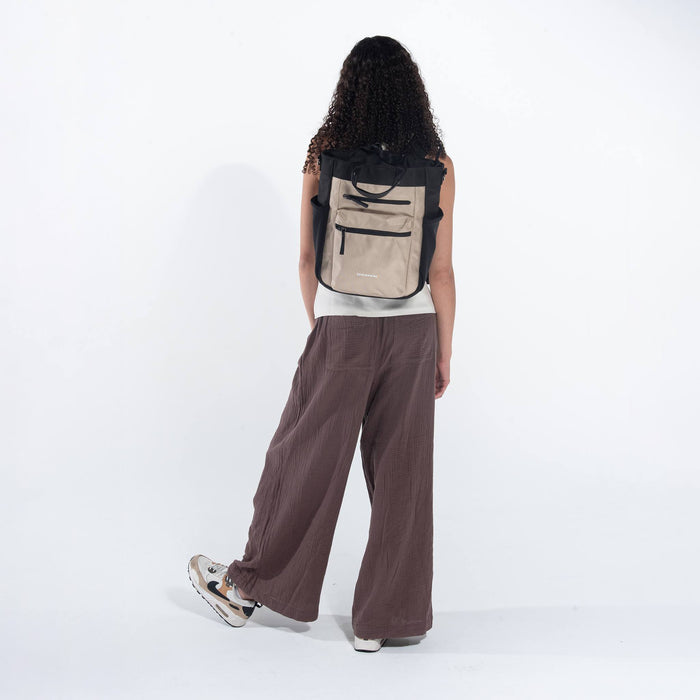 Woman wearing Sherpani Soleil Straw Beige Anti-theft Multi-Wear Travel Bag on her back against white backdrop.  #color_straw-beige