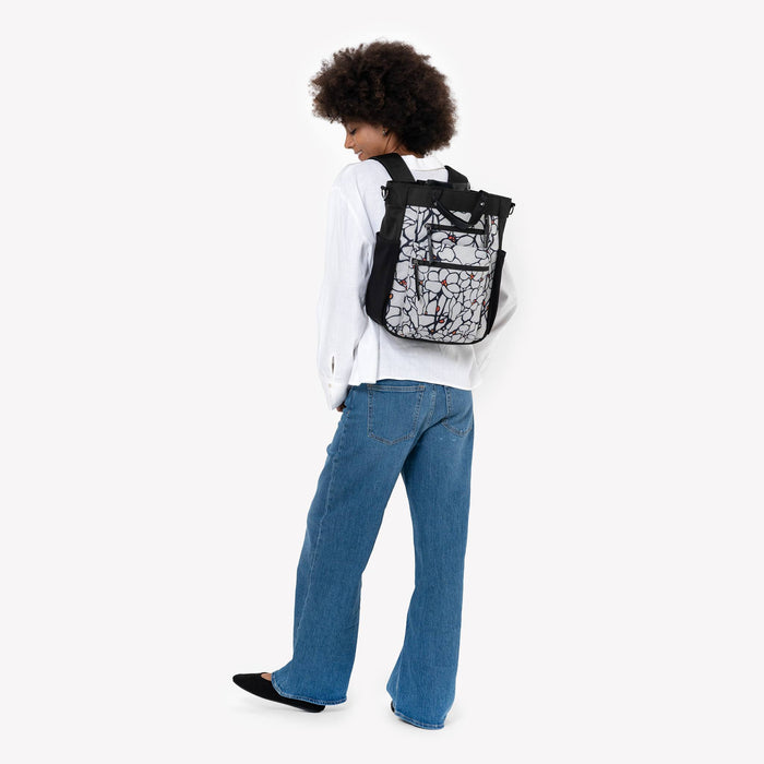 Woman wearing Sherpani Soleil Sakura Anti-theft Multi-Wear Travel Bag on her back against white backdrop. #color_sakura-signature