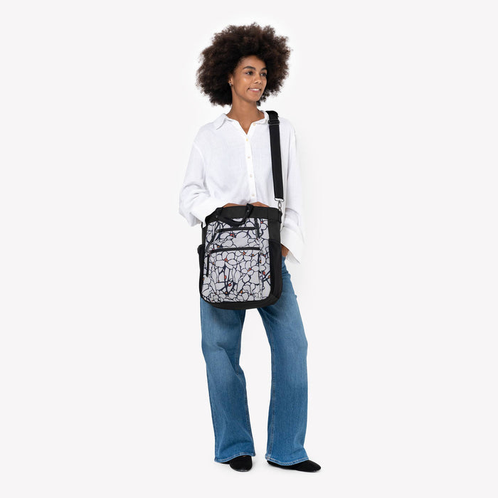 Woman wearing Sherpani Soleil Sakura Anti-theft Multi-Wear Travel Bag on her shoulder against white backdrop. #color_sakura-signature