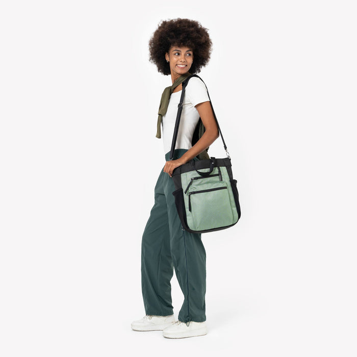 Woman wearing Sherpani Soleil Aloe Mist Green Anti-theft Multi-Wear Travel Bag on her shoulder against white backdrop. #color_aloe-mist