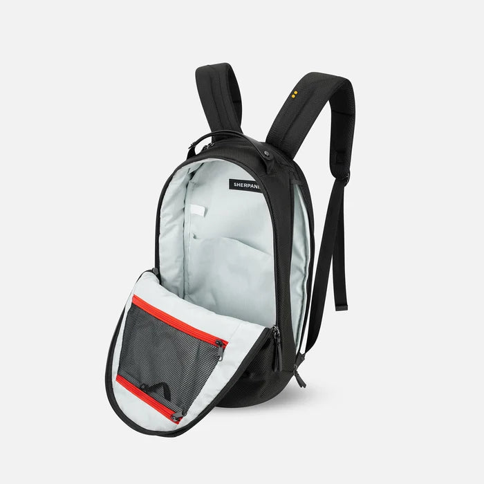 A Sherpani Solstice Carbon Black Anti-Theft Travel Backpack, 3/4 view showing the inside of the main and side pocket against a white background. #color_carbon-black
