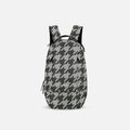 A Sherpani Solstice Houndstooth Anti-Theft Travel Backpack, front view showing front pockets and different straps on white background. #color_houndstooth-print