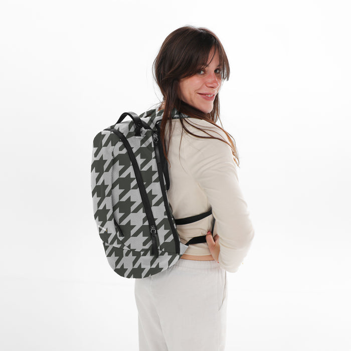 A woman wearing a Sherpani Solstice Houndstooth Anti-Theft Travel Backpack on her back against a white background.   #color_houndstooth-print