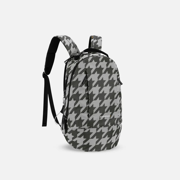 A Sherpani Solstice Houndstooth Anti-Theft Travel Backpack, 3/4 view showing back strap pockets and different strap options against a white background. #color_houndstooth-print