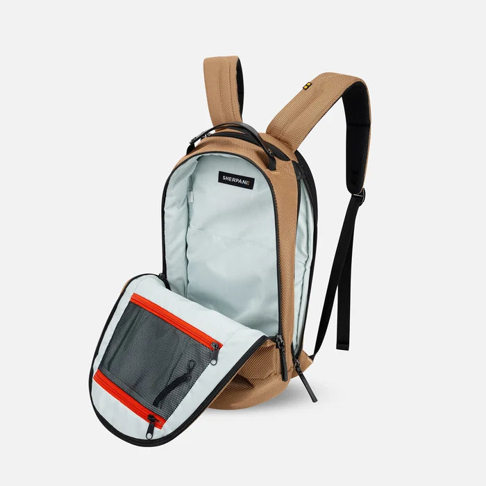 A Sherpani Solstice Sand Tan Anti-Theft Travel Backpack, 3/4 view showing the inside of the main and side pocket against a white background.  #color_sand-tan
