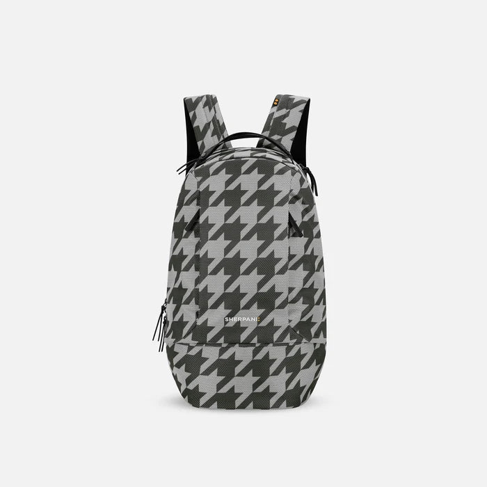 A Sherpani Solstice Houndstooth Anti-Theft Travel Backpack, front view showing front pockets and different straps on white background. #color_houndstooth-print
