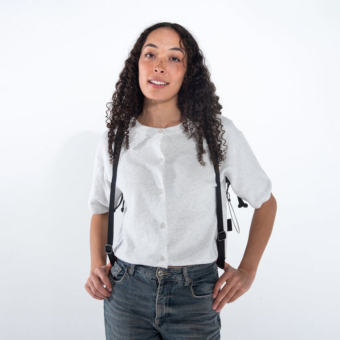 Woman wearing a Sherpani Tempest Carbon Black Convertible Tote on her back against white background. #color_carbon-black