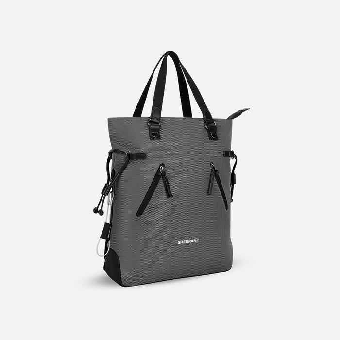 A Sherpani Tempest Granite Grey Convertible Tote, 3/4 view showing tote straps & front lockable pockets on white backdrop.  #color_granite-grey